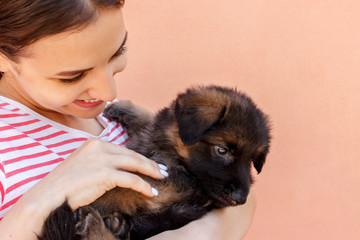 Young woman keeping black German shepherd puppy near her face