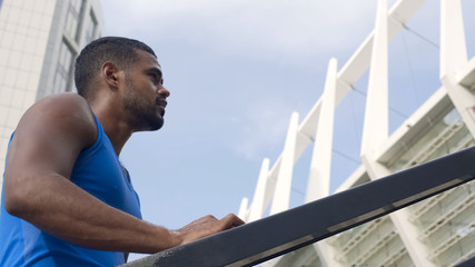 Sweating male athlete standing on staircases, jogging for fit body, active life