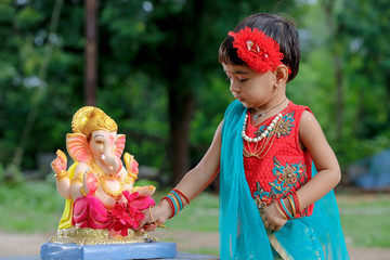 Little Indian girl child with lord ganesha and praying , Indian ganesh festival
