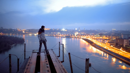 Happy man standing on top of bridge looking at beautiful night city, freedom © motortion