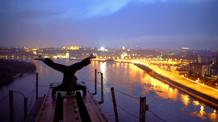 Courageous athlete making headstand on edge of bridge, adrenaline and sports © motortion
