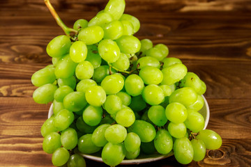 Tasty fresh white grape in a plate on wooden table