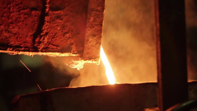 The molten metal flows out of the furnace. Modern metallurgical industry.