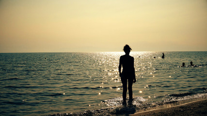 Silhouette fashion model out of sea water at sunset, sunrise