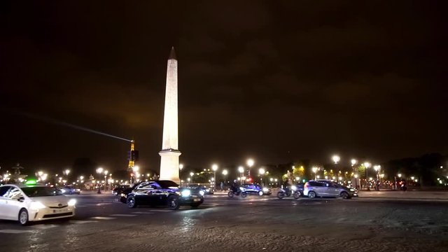 Traffic at place de la concorde at night with view of obelisk and Eiffel tower lights at background, slow motion