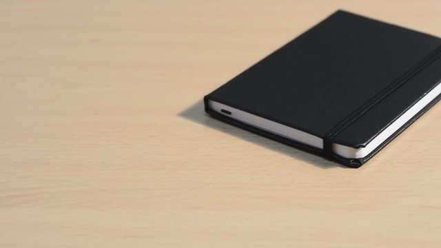 Lapicero y libreta negra en la mesa
