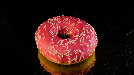 Food concept, the concept of an unpleasant but delicious food. Donut on a black background.