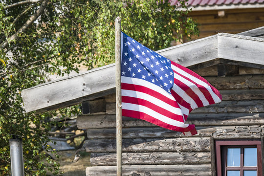 The flag of USA outside a wooden cabin