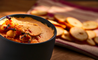 Bowl full of hummus including paprika, chickpeas, lavender and bread