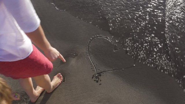 Woman Tracing Heart Shape on Beach Sand