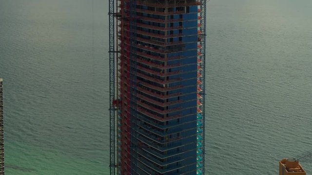 Aerial footage of a tall building under construction with clouds in background