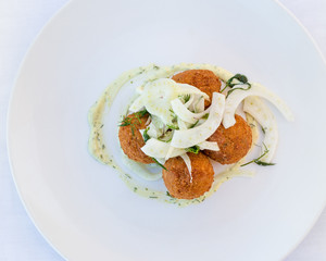 Flatlay of croquette on a white plate with fennel.