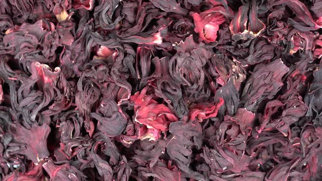 Large leaves of hibiscus red dry tea background, close up. Loop rotation. Front of the camera rotates plate with hibiscus red dry tea, macro