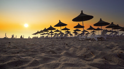 TRAVEL VACATION CONCEPT. Wonderful sunset at the empty beach with loungers and wooden sheds