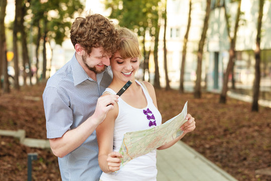 Tourist couple in city looking up directions on map