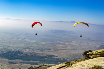 Paragliding flight with blue sky and misty valley