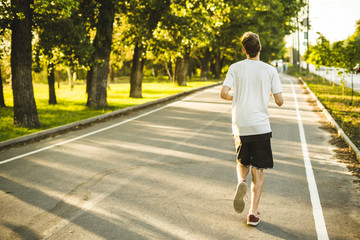 Fototapeta premium young man running in the morning in the city park durnig sunrise