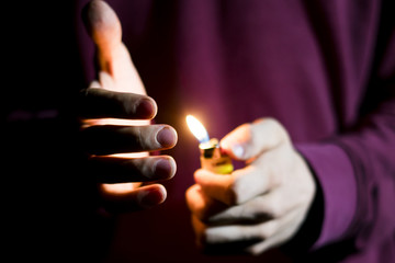 close up hands holding gas lighter in the dark - obrazy, fototapety, plakaty