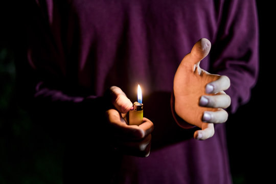 close up hands holding gas lighter in the dark