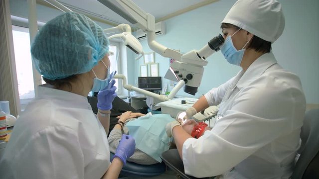 Doctor Used Microscope. Dentist Is Treating Patient In Modern Dental Office
