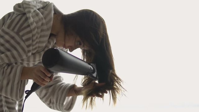 Young beautiful girl dries hair with a hair dryer