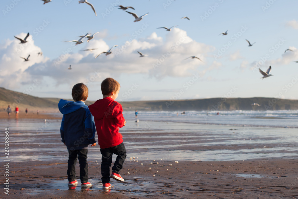 Sticker Two adorable kids, feeding the seagulls on the beach