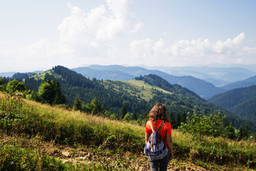 Naklejka na ściany i meble Girl in the mountains, a traveler photographed from the back