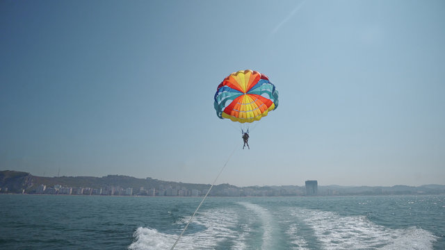 Excited tourists parasailing high in the sky, extreme sport, summer activities