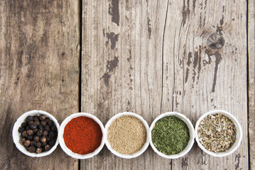 Various spices on wooden rustic background: rosemary, paprika, black pepper. Top view. Copy space.