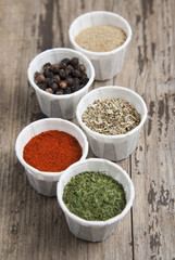 Various spices on wooden rustic background: rosemary, paprika, black pepper. Top view.