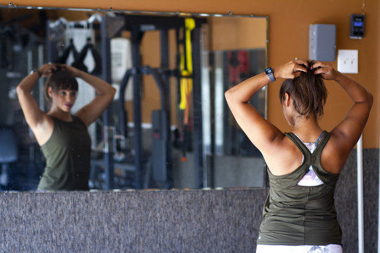 Beautiful Latina Woman fixes her hair at the gym
