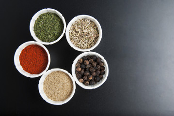 Various spices on black background: rosemary, paprika, black pepper. Top view. Copy space.