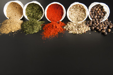 Close up various spices on black background: rosemary, paprika, black pepper. Copy space.