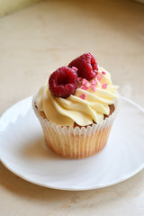 Vanilla cupcakes with fruits on top.