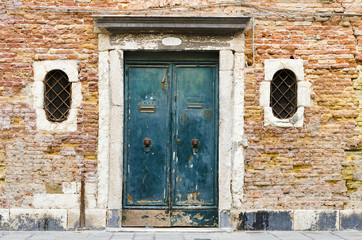 Fototapeta na wymiar Burano island near Venice, Italy - House with dark red very old facade, wooden door and two symmetrical windows, concept of restore, solution ,construction