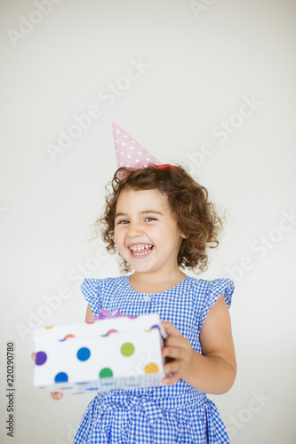 Pretty Baby Girl With Dark Curly Hair In Dress And Birthday Cap