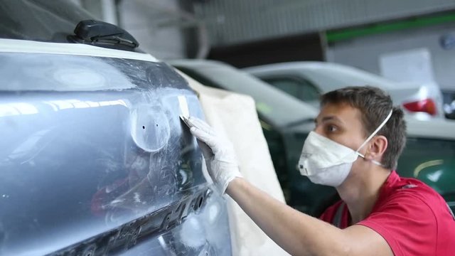 automotive repair. mechanic puttying car body