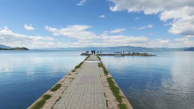 Moving on fishermans port on Ohrid lake with calm water reflection and blue sky