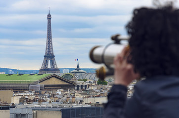 Woman looking through coin operated binocular at Eiffel Tower in Paris, France