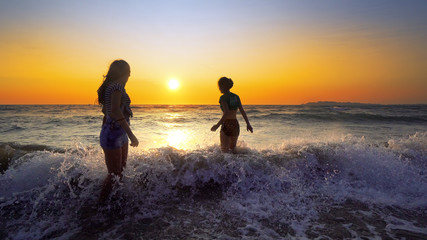 Fototapeta premium Young fun party of people dancing and spraying at the beach sunset.Concept of friendly family.