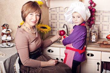 Young grandmother with her grandchildren on the kitchen making dinner together. Ideal family...