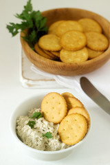 Snack from crackers and curd fish paste with herbs on a light background.