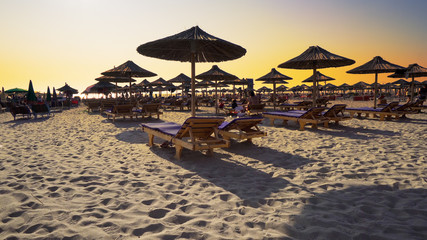 Luxury summer beach resort with straw umbrellas at sunset, cinematic steadicam shot
