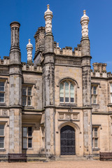 Fototapeta na wymiar Edinburgh, Scotland, UK - June 14, 2012: Main entrance and tower of Dalmany house, mansion and castle in Tudor revival style. Blue sky.