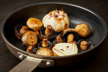 delicious fried mushrooms on a hot pan on an old wooden black table