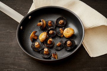 delicious fried mushrooms on a hot pan on an old wooden black table