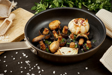delicious fried mushrooms on a hot pan on an old wooden black table