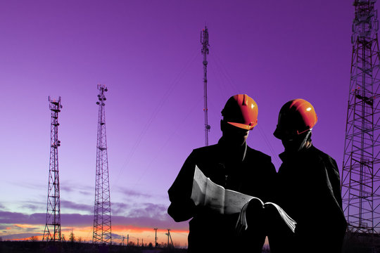 Silhouette of professional industrial climber in helmet and uniform works at height for instaling communication equipment and antenna and telecommunication towers with sunset sky as background. Risky