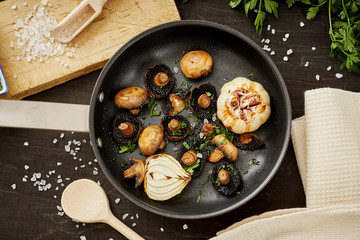 delicious fried mushrooms on a hot pan on an old wooden black table