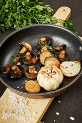 delicious fried mushrooms on a hot pan on an old wooden black table